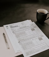black ceramic mug beside white printer paper